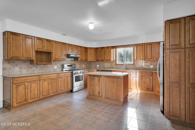 kitchen featuring appliances with stainless steel finishes, backsplash, extractor fan, sink, and a kitchen island