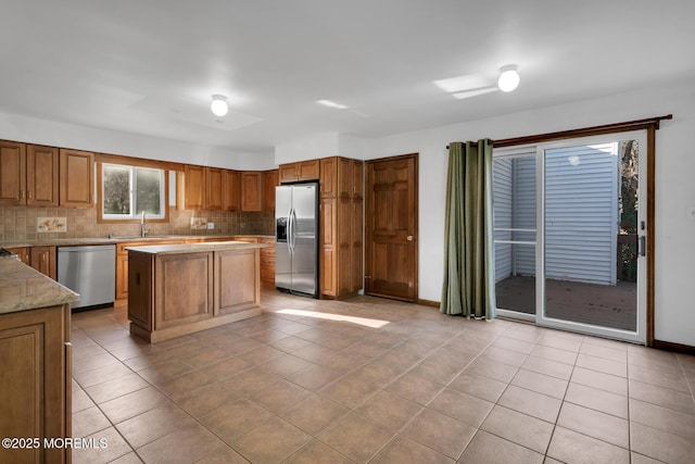 kitchen with a center island, sink, light tile patterned floors, tasteful backsplash, and stainless steel appliances