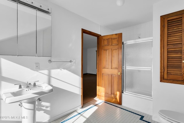 bathroom with bath / shower combo with glass door and toilet