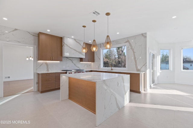 kitchen featuring tasteful backsplash, sink, exhaust hood, a kitchen island, and hanging light fixtures