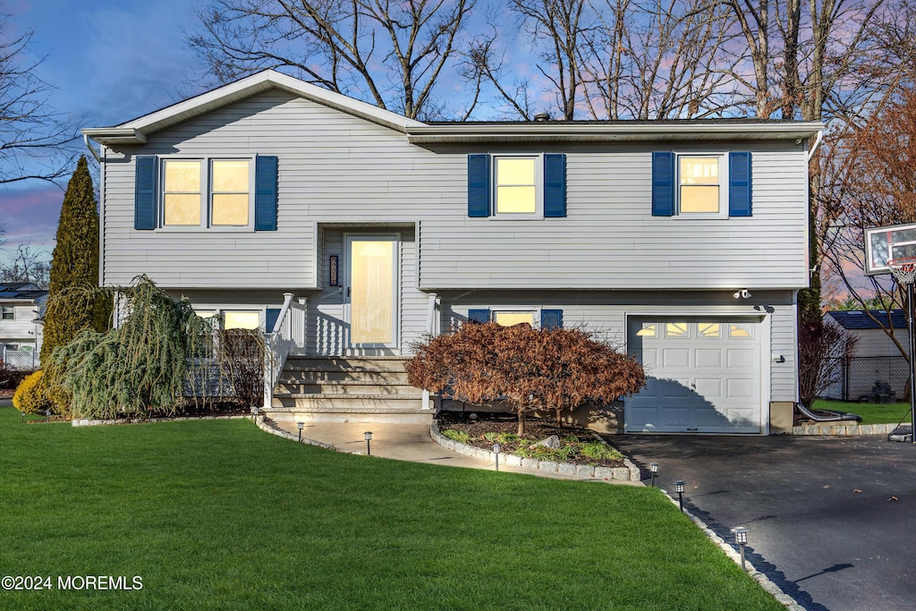 split foyer home with a yard and a garage