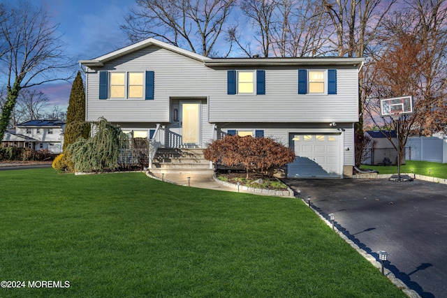 raised ranch featuring a garage and a yard