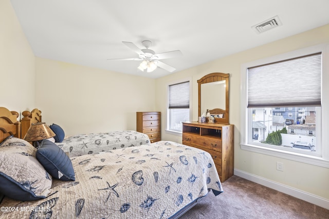 carpeted bedroom with ceiling fan and multiple windows