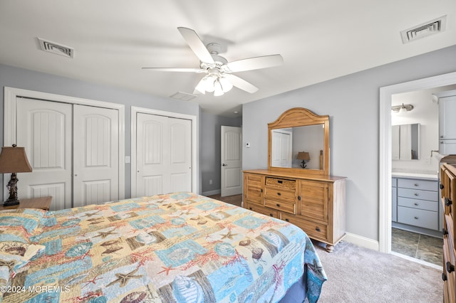 carpeted bedroom featuring ceiling fan, ensuite bath, and multiple closets