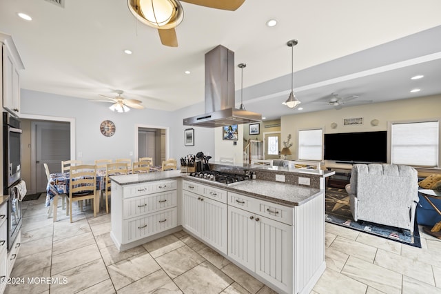 kitchen with dark stone counters, white cabinets, hanging light fixtures, island exhaust hood, and stainless steel appliances