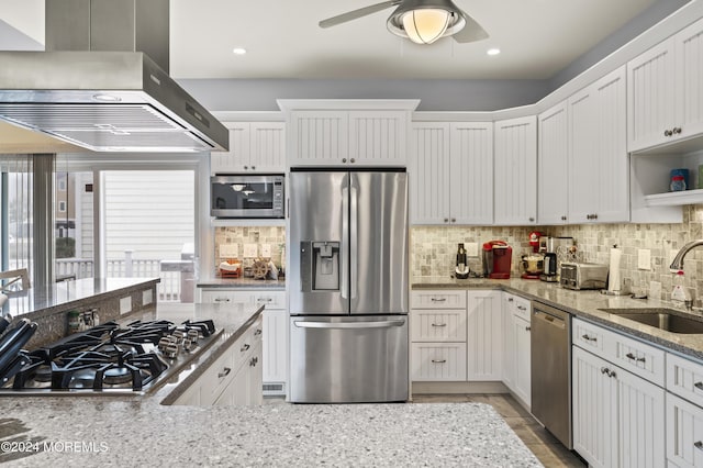 kitchen with stainless steel appliances, white cabinetry, wall chimney exhaust hood, and sink