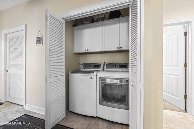 laundry area with cabinets, washing machine and dryer, and light tile patterned flooring