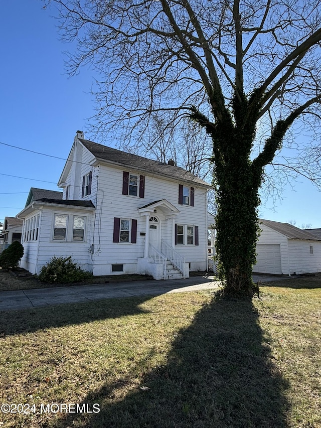 view of front of home with a front yard, a garage, and an outdoor structure