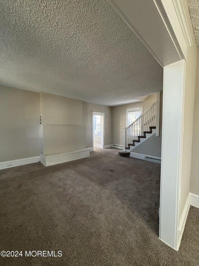 unfurnished living room with a textured ceiling, dark carpet, and baseboard heating