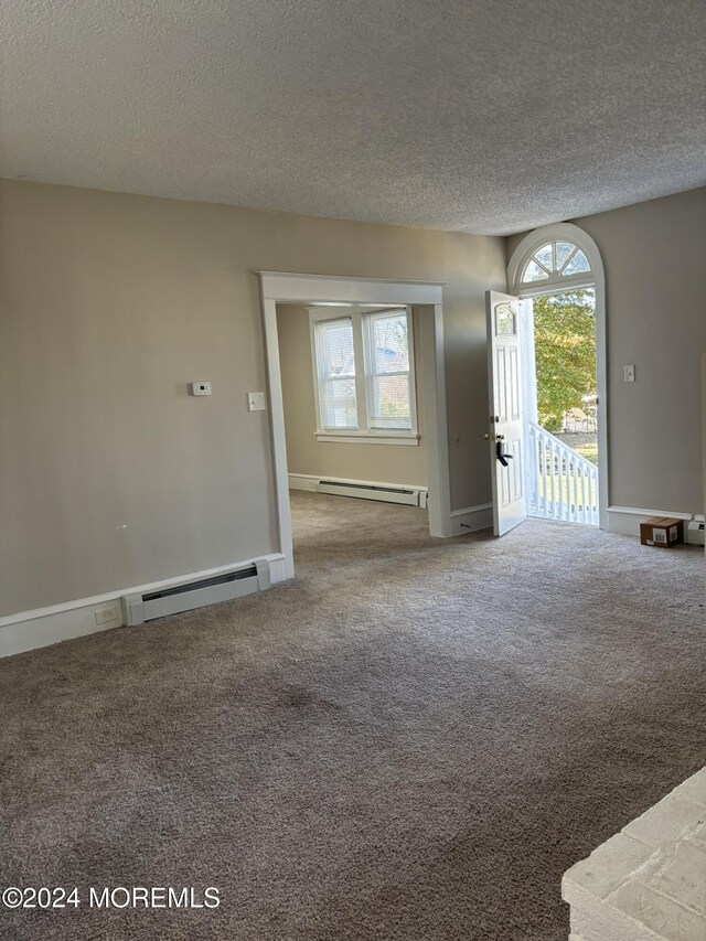 carpeted spare room with a textured ceiling and a baseboard radiator