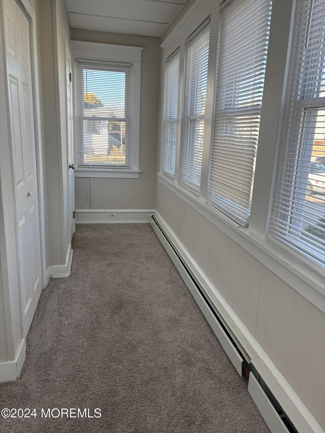 unfurnished sunroom featuring a baseboard heating unit