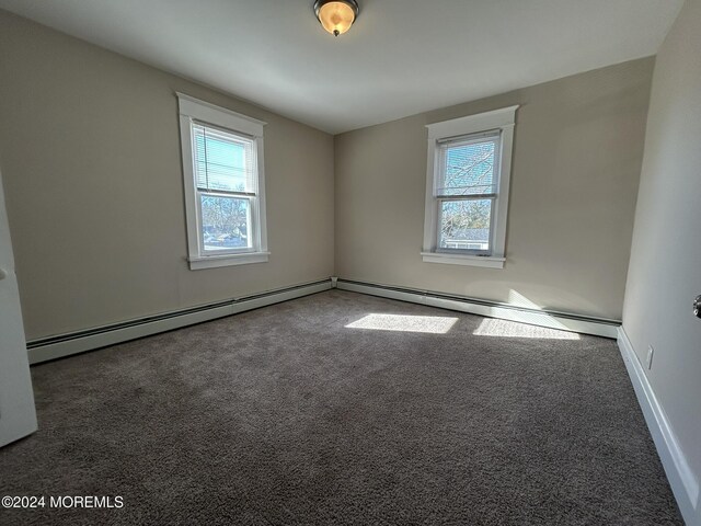 carpeted spare room featuring a baseboard radiator