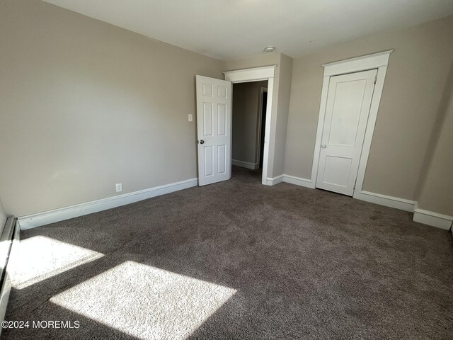 unfurnished bedroom with dark carpet