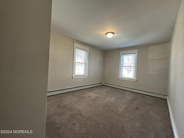 empty room featuring carpet flooring, baseboard heating, and a healthy amount of sunlight