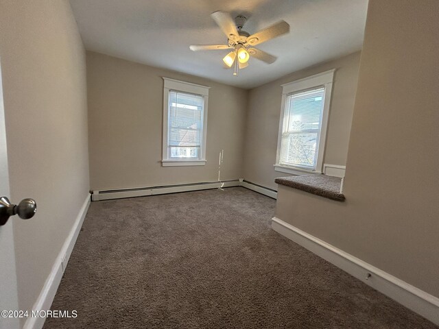 empty room with a wealth of natural light, carpet, a baseboard heating unit, and ceiling fan