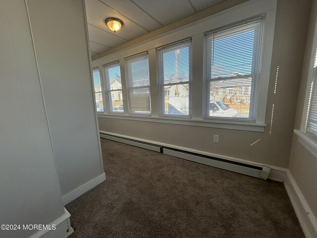 carpeted empty room featuring baseboard heating