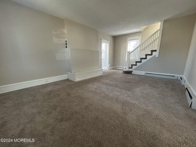 unfurnished living room featuring a textured ceiling, dark carpet, and a baseboard heating unit