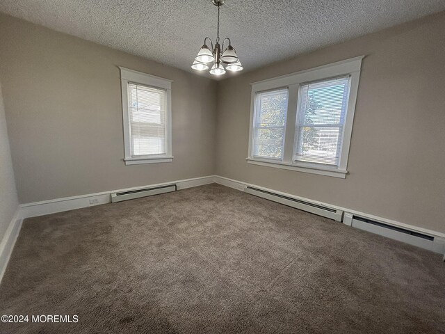 unfurnished room with a textured ceiling, carpet, a notable chandelier, and a baseboard heating unit