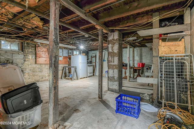 basement featuring electric panel and white fridge