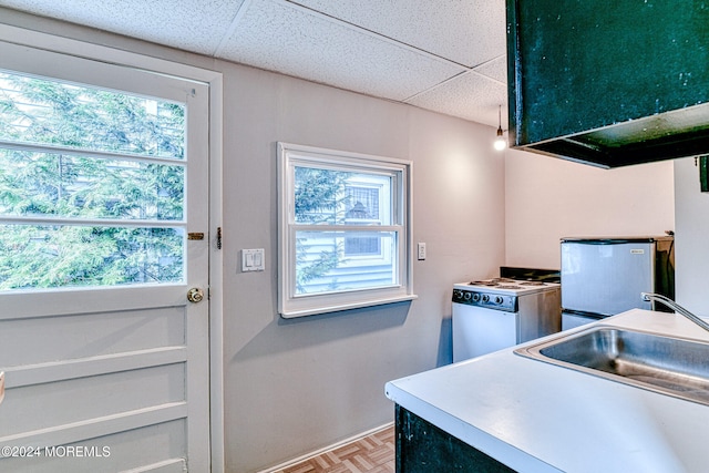 kitchen with a paneled ceiling, parquet floors, white range, sink, and extractor fan