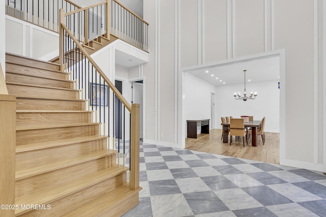 stairway featuring a chandelier, a high ceiling, and hardwood / wood-style floors