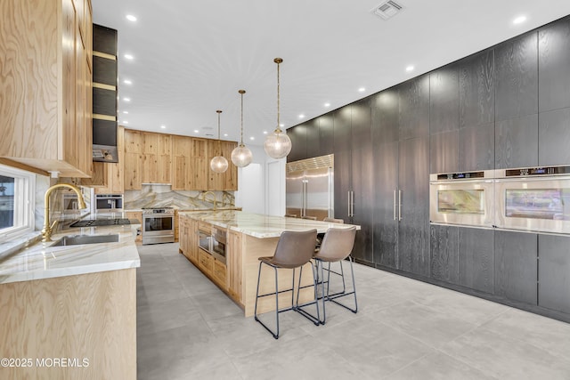 kitchen with light stone countertops, stainless steel appliances, sink, hanging light fixtures, and a large island