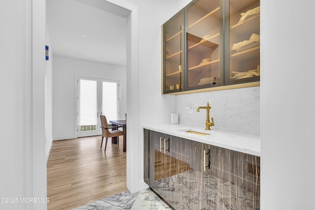 bar featuring decorative backsplash, light wood-type flooring, and sink