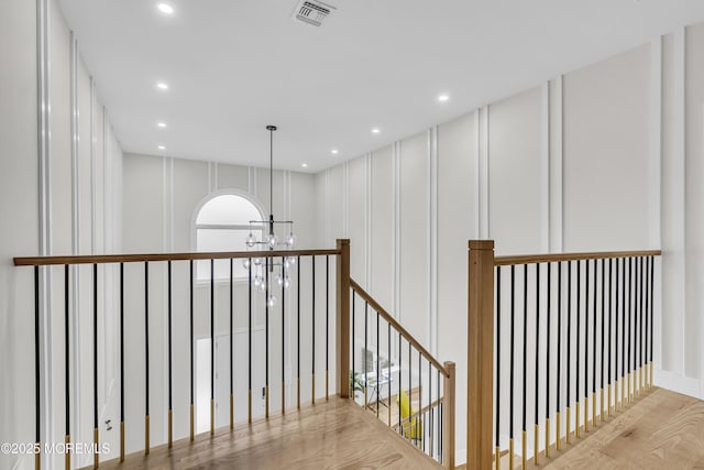 hallway featuring light wood-type flooring and a chandelier