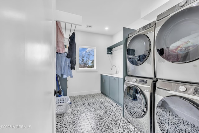 washroom featuring cabinets, light tile patterned floors, stacked washer / drying machine, and sink