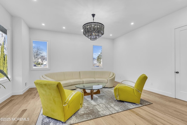 living room with light wood-type flooring, an inviting chandelier, and a healthy amount of sunlight