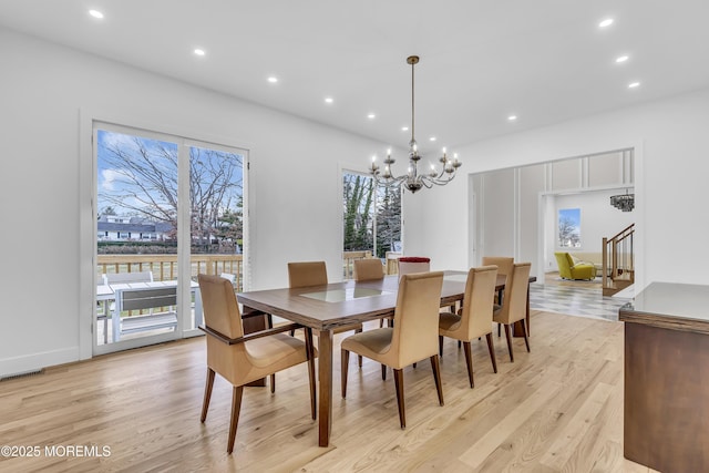 dining area with light wood-type flooring and a notable chandelier