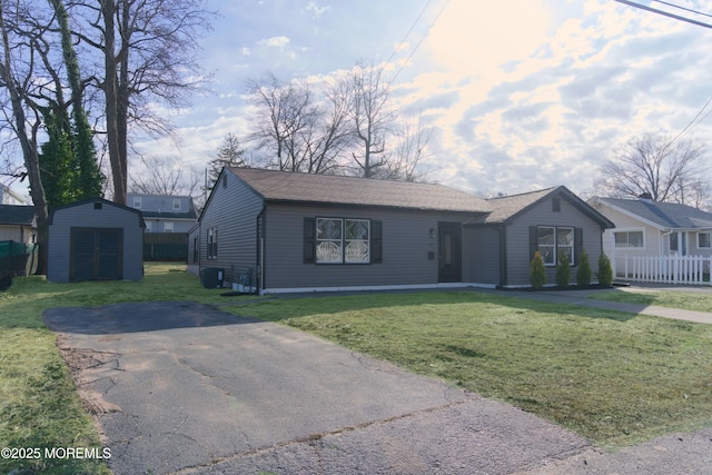 ranch-style house featuring a front lawn and a storage unit