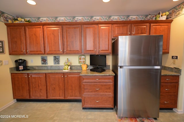 kitchen featuring light tile patterned flooring, stainless steel fridge, and dark stone countertops