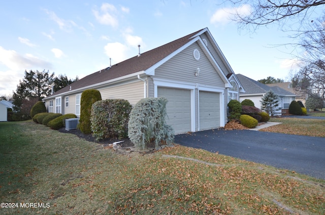 view of side of home with a lawn, central air condition unit, and a garage