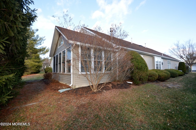 view of side of property with a sunroom and a lawn