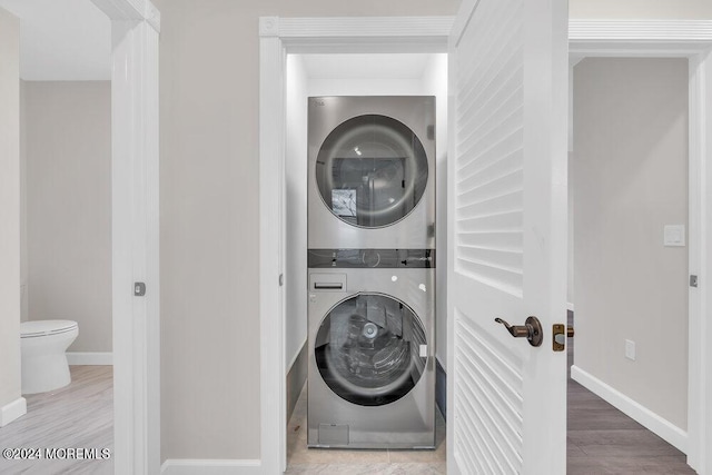 clothes washing area featuring hardwood / wood-style flooring and stacked washer / drying machine