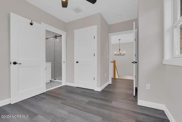 interior space with wood-type flooring, ceiling fan with notable chandelier, and ensuite bathroom