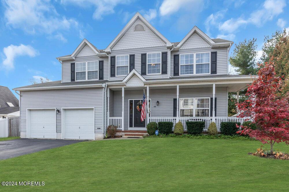 view of front of home featuring a porch, a garage, and a front lawn