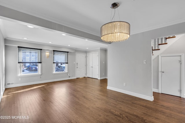 unfurnished living room with dark hardwood / wood-style floors, crown molding, and a chandelier