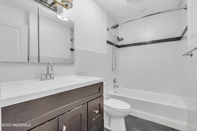 full bathroom with tiled shower / bath combo, tasteful backsplash, toilet, vanity, and tile walls