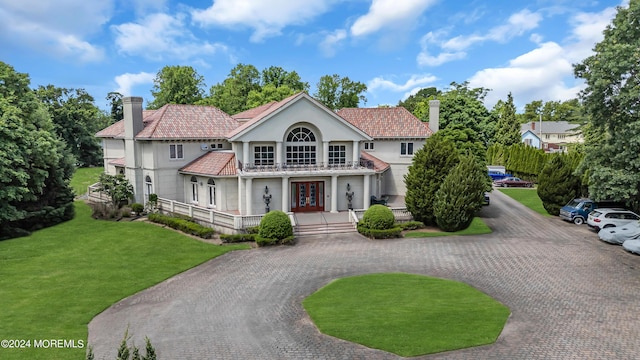 view of front of home with a front lawn, a porch, a balcony, and french doors