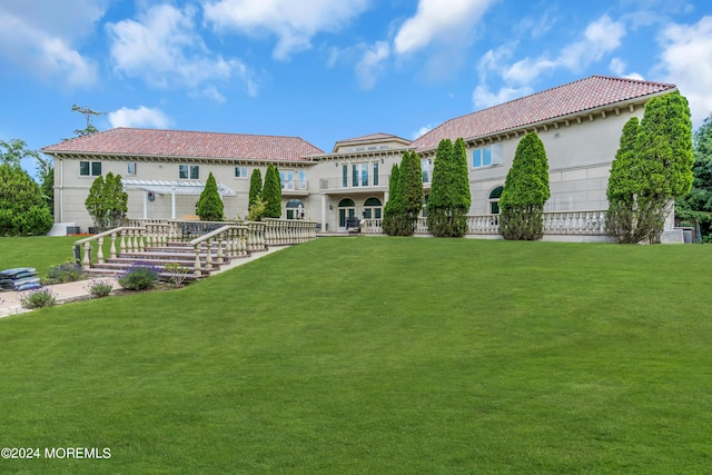 back of property with a yard and a balcony