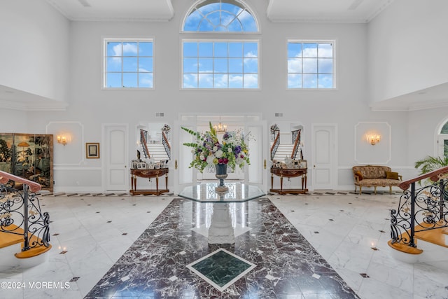 entryway with crown molding, a towering ceiling, and a notable chandelier