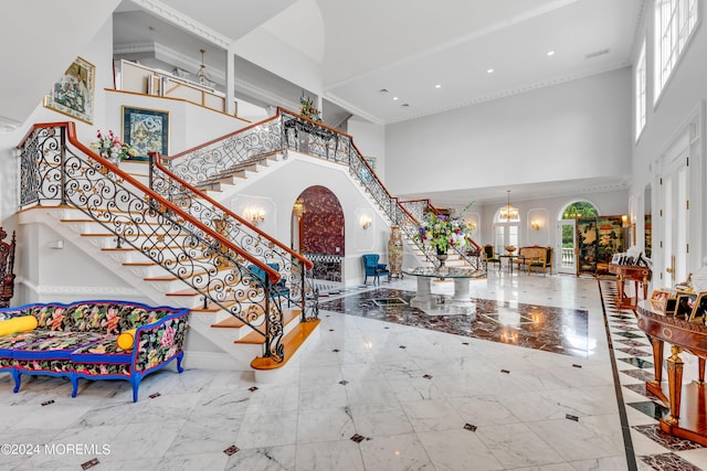 entrance foyer with a towering ceiling, an inviting chandelier, and ornamental molding