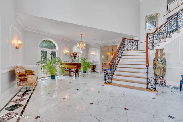 interior space with french doors, a towering ceiling, ornamental molding, and a notable chandelier