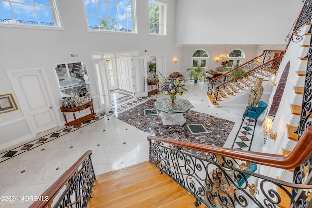 tiled entryway featuring a towering ceiling, french doors, and an inviting chandelier