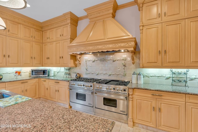 kitchen with light stone countertops, stainless steel appliances, backsplash, light tile patterned floors, and custom exhaust hood