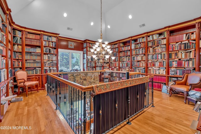 living area with a chandelier, wood-type flooring, and lofted ceiling