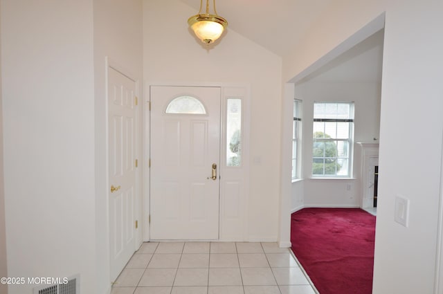 foyer featuring a premium fireplace, lofted ceiling, and light tile patterned flooring