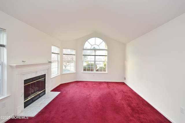 unfurnished living room featuring a high end fireplace, light colored carpet, and vaulted ceiling